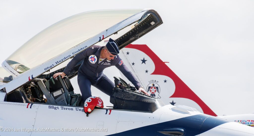 A U.S. Air Force pilot in uniform climbs into the cockpit of a Thunderbirds jet with its canopy open.