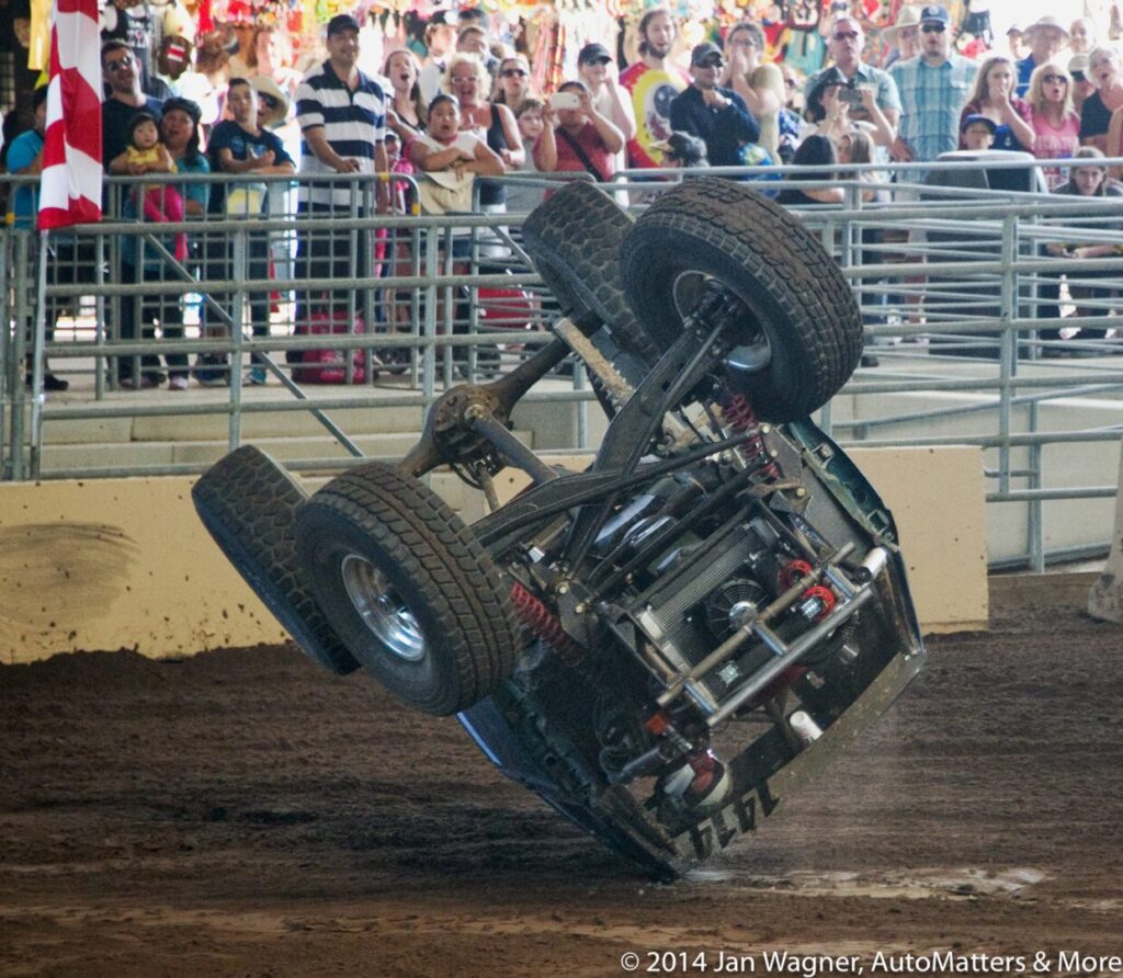 A person doing a flip in a dirt arena.