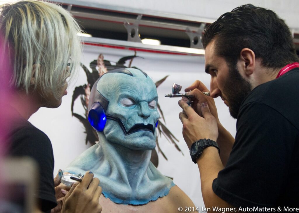 A man is painting a man's face with blue paint.