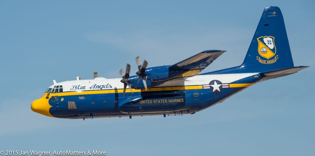 A blue and yellow military plane flying through the air.