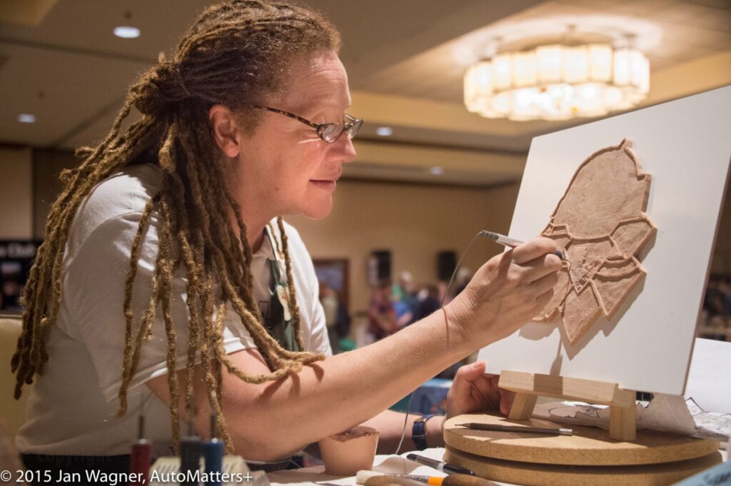 A woman with dreadlocks working on a piece of art.
