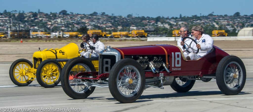 Two men are driving a vintage car on a runway.