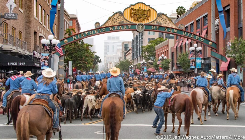A group of cowboys riding horses down a city street.