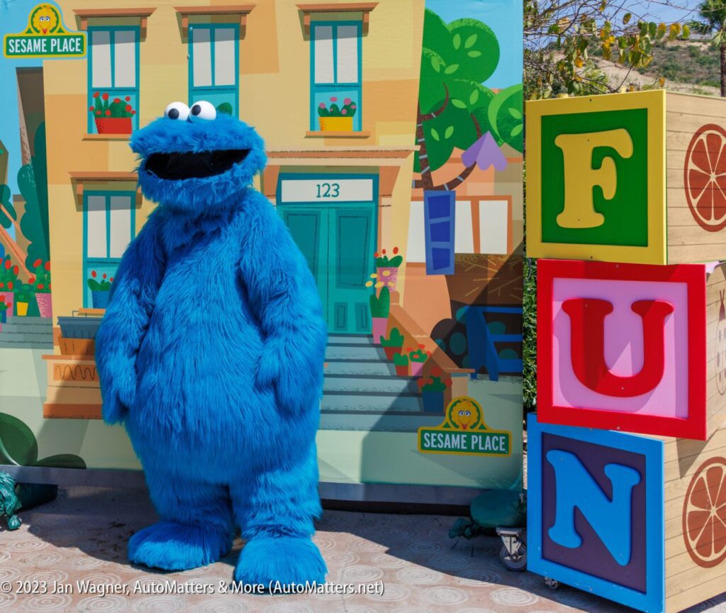 A blue cookie monster mascot standing in front of a building.
