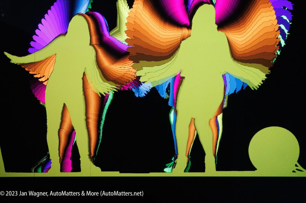 A group of people with colorful wings standing in front of a light.
