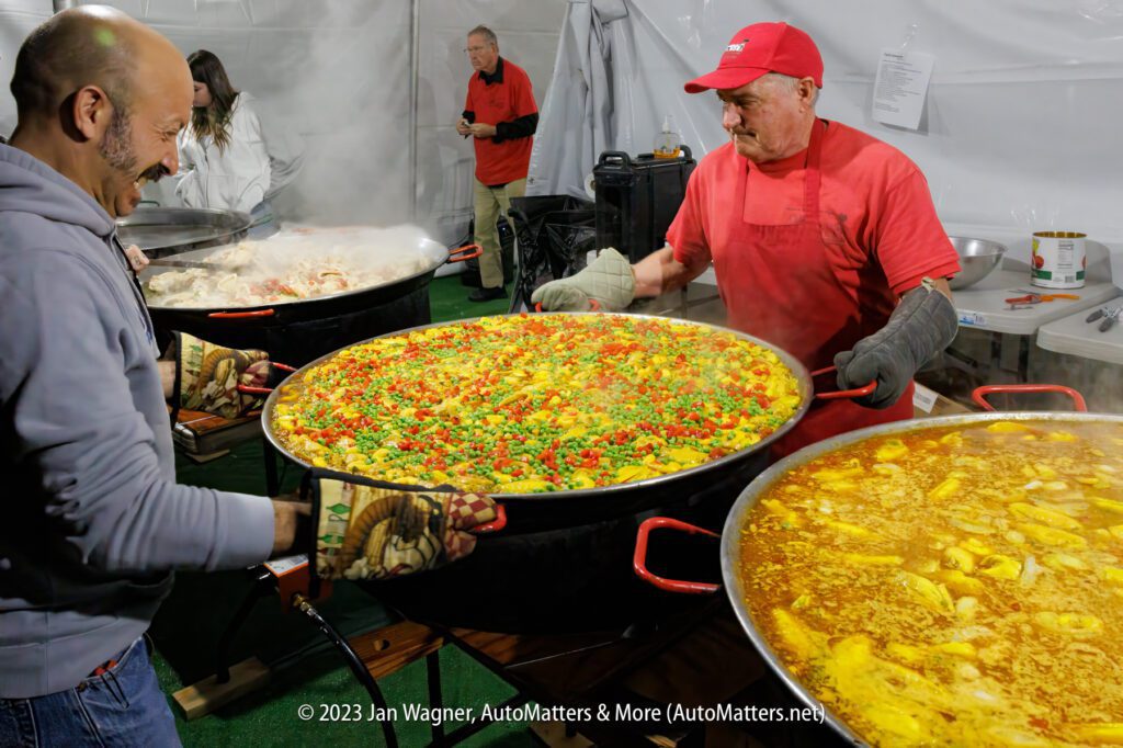 A man is preparing a large pot of paella.