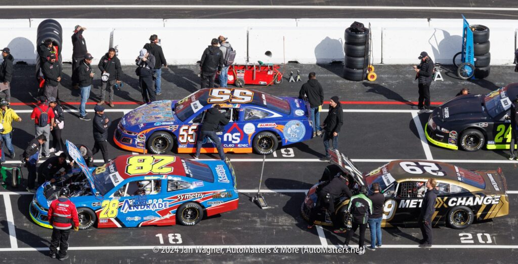 A group of nascar cars parked in a parking lot.