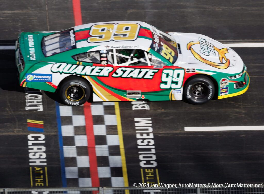 A green and white nascar car on a track.