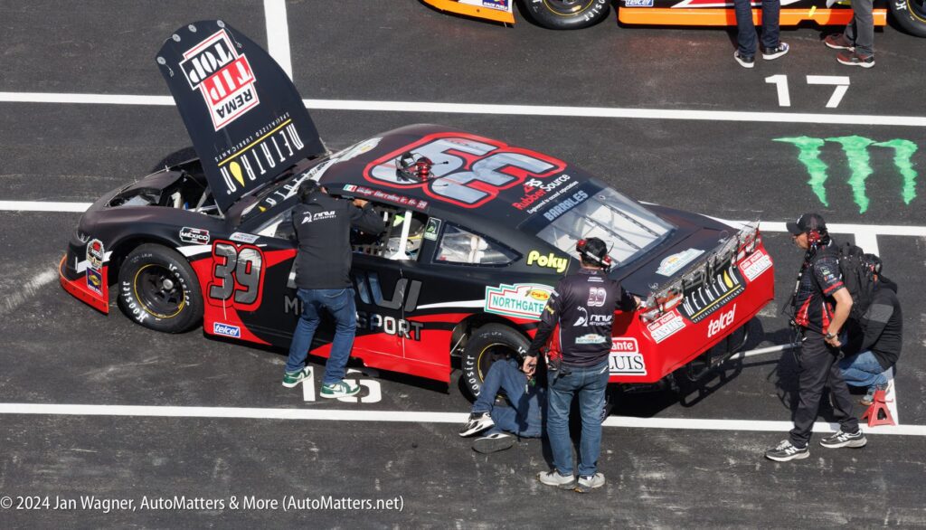 A nascar car is being worked on by a team of men.