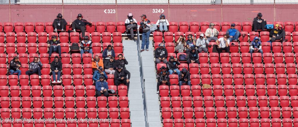 A group of people sitting on red seats in a stadium.