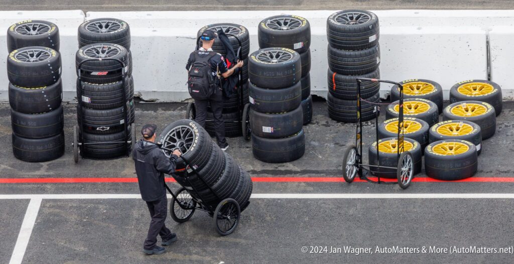 A group of men standing next to a cart full of tires.