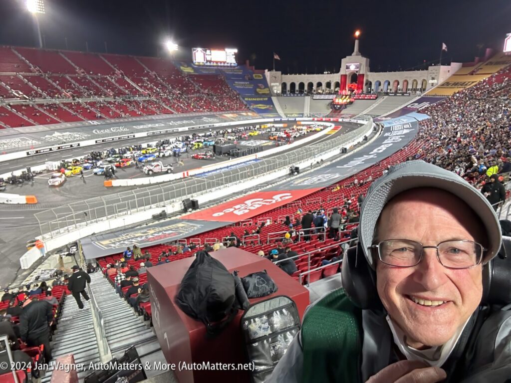 A man taking a selfie in front of a large stadium.