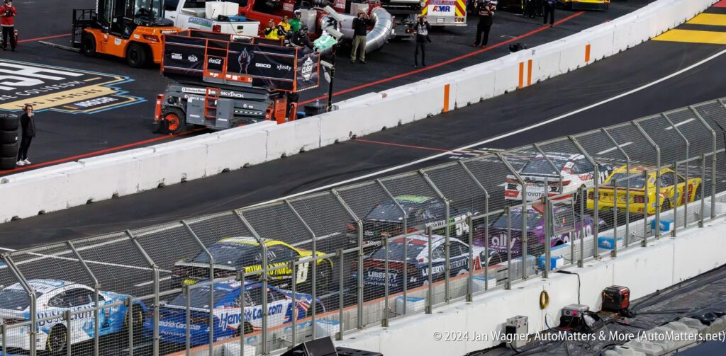 A nascar race with several cars on the track.