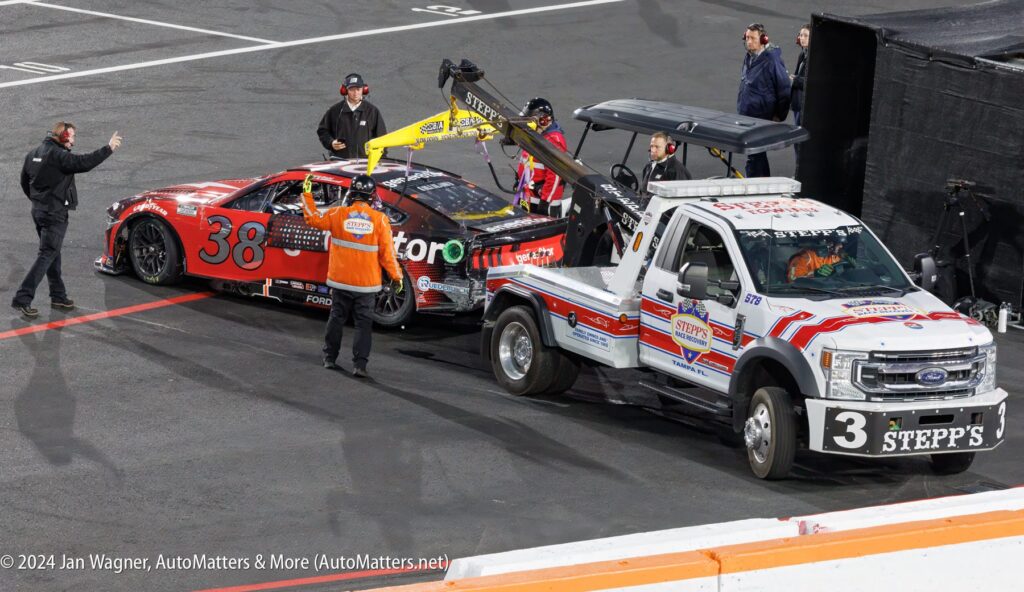 A tow truck is being used to tow a race car.