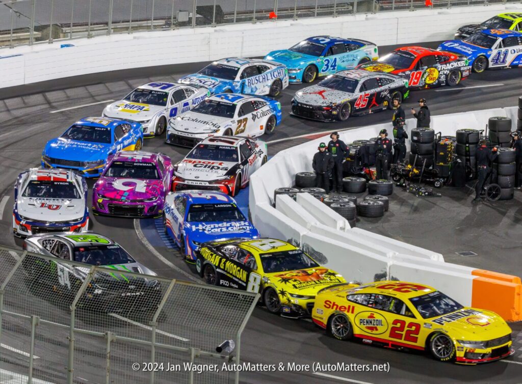 A group of nascar cars in a race track.