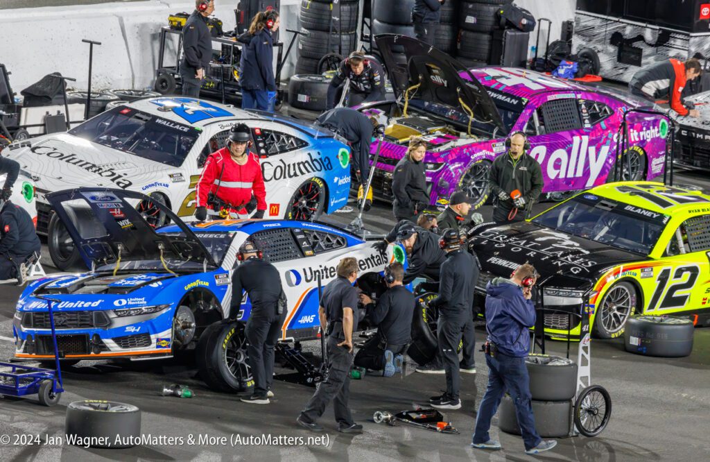 A group of nascar drivers working on their cars.