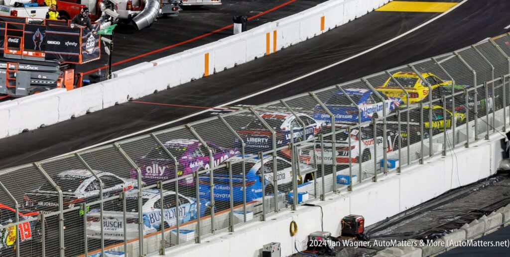 Nascar cars are lined up on a track.