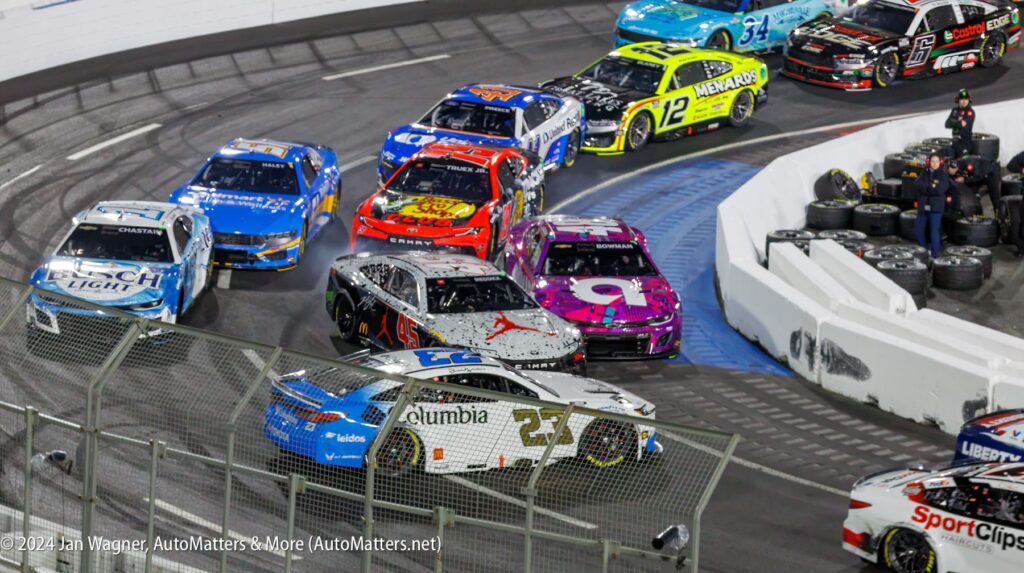 A group of nascar cars racing around a track.