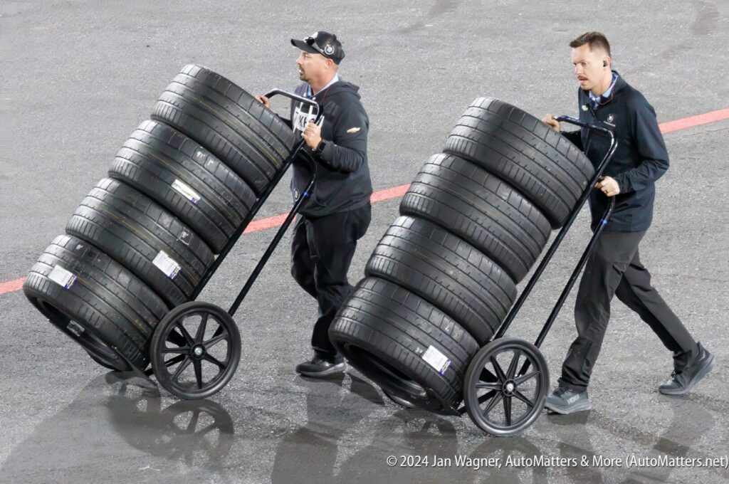 Two men carrying a cart full of tires.