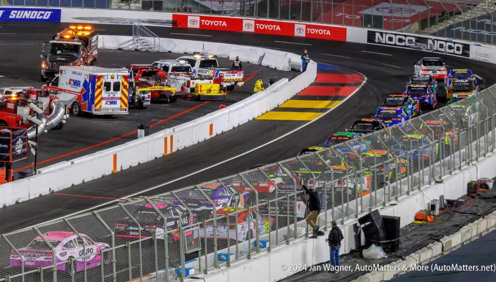 A race track with a row of cars and a fence.