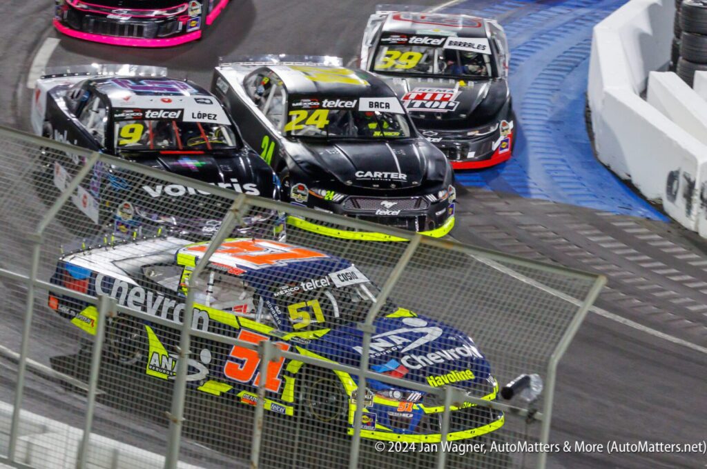 A group of nascar cars in a race.
