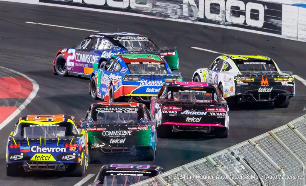 A group of nascar cars racing on a track.