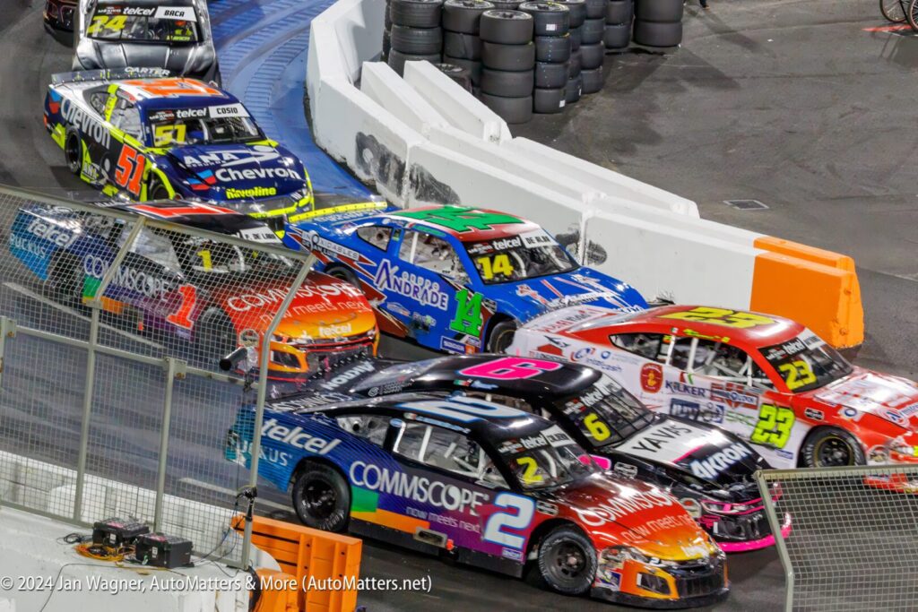 A group of nascar cars in a race track.