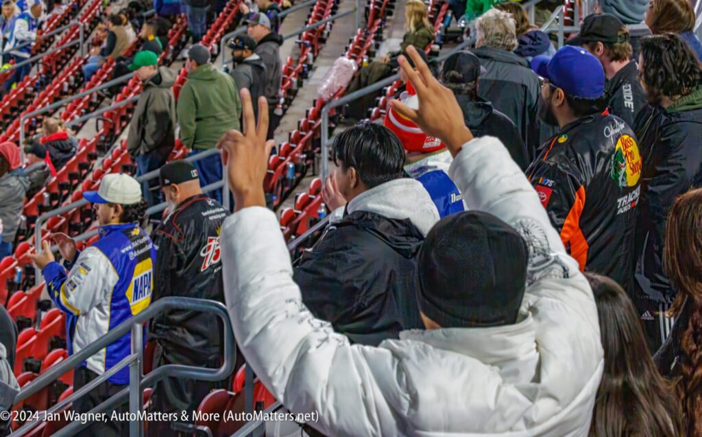 A group of people in the stands at a race.