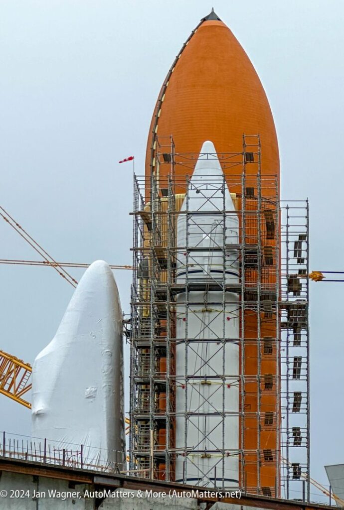 A large orange space shuttle is under construction.