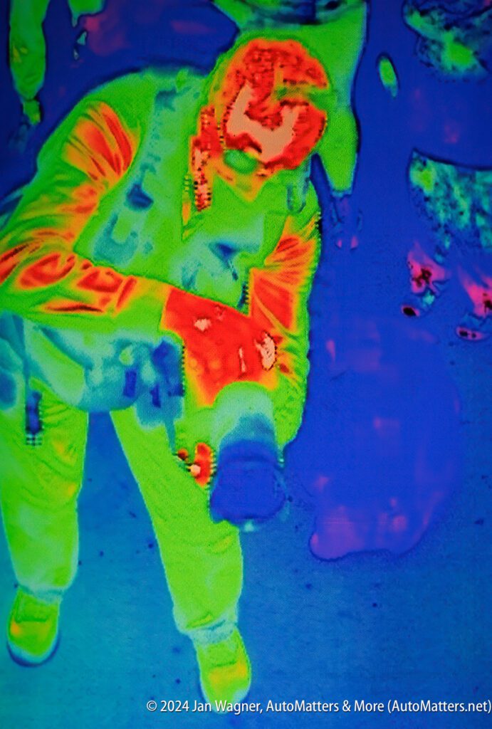 An infrared image of a person holding a camera.