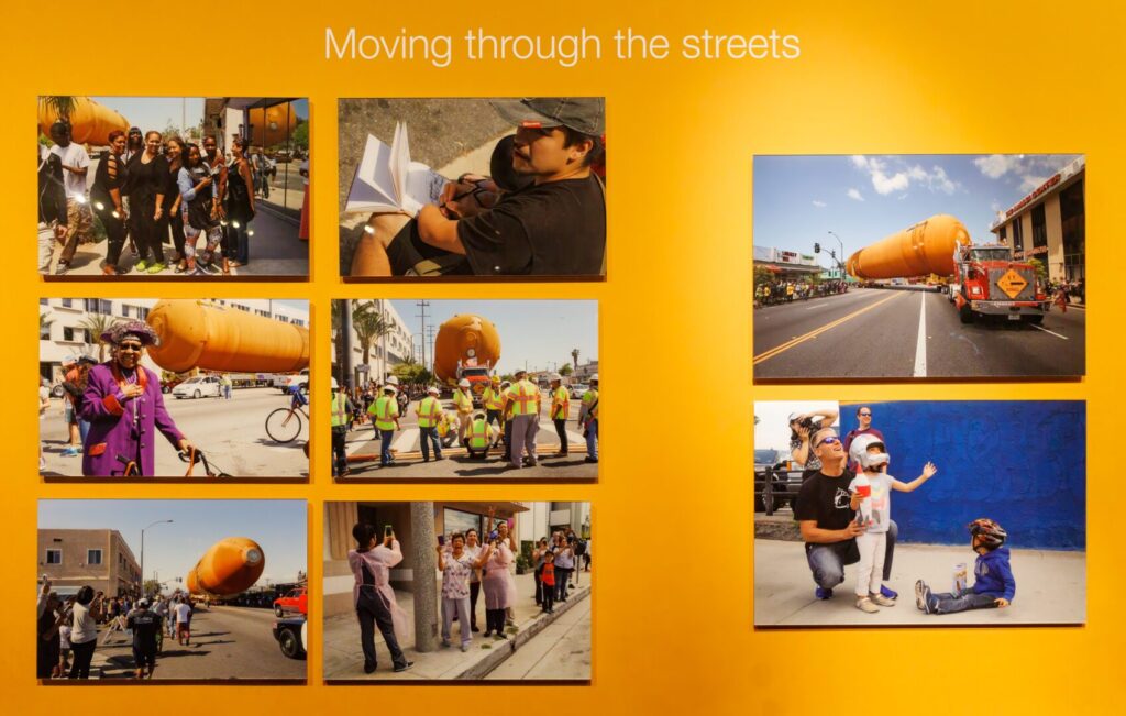 An orange wall with pictures of people moving through the streets.
