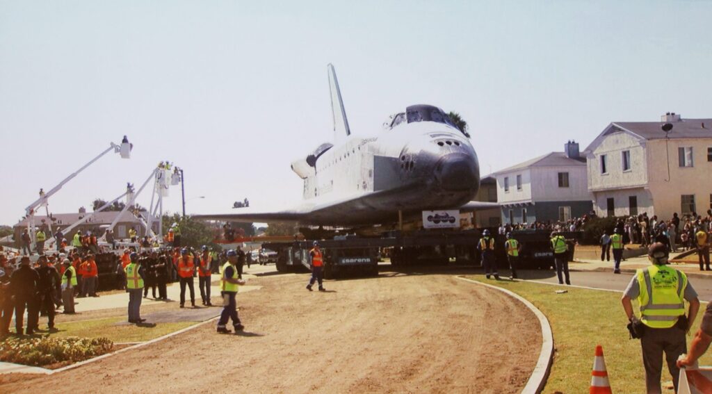 A space shuttle is being loaded onto a truck.