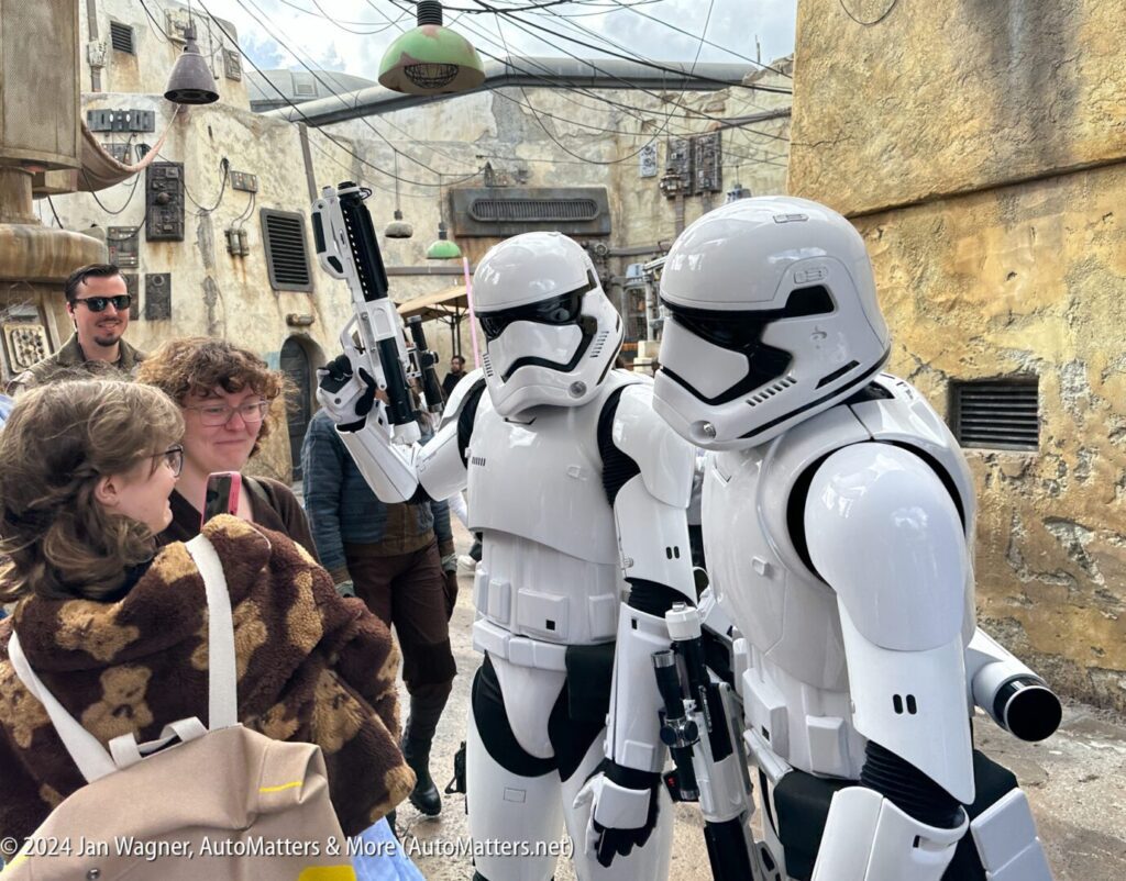 A group of people are talking to a group of stormtroopers.