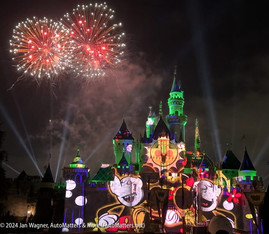 Disneyland castle lit up with fireworks in the night sky.