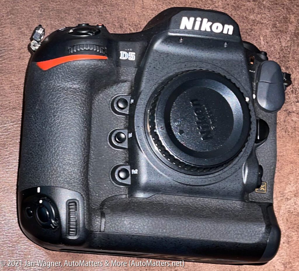 Nikon D5 camera body on a brown surface, viewed from above.