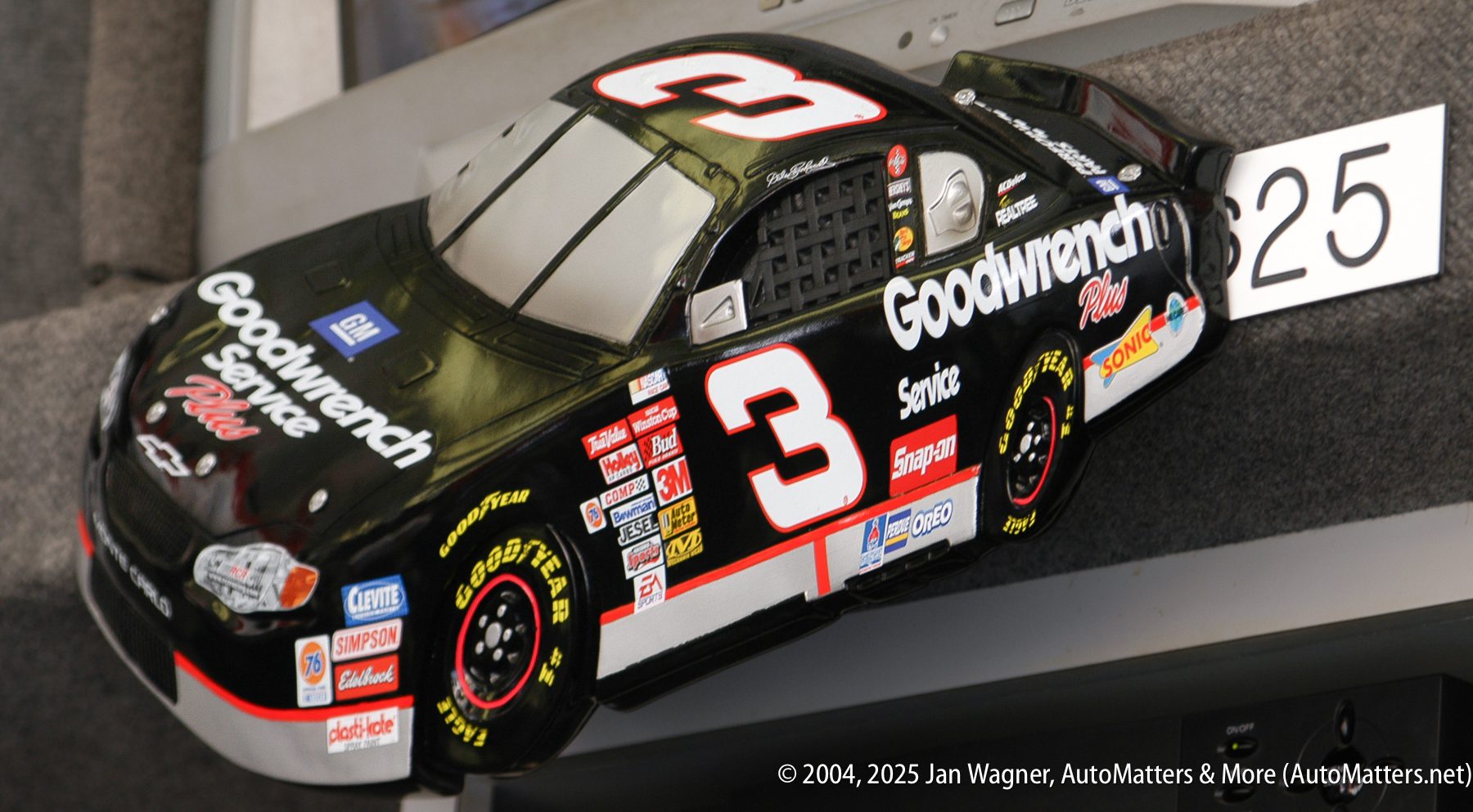 A black No. 3 Goodwrench Service Plus race car model is displayed on a gray surface with the number 25 label next to it.