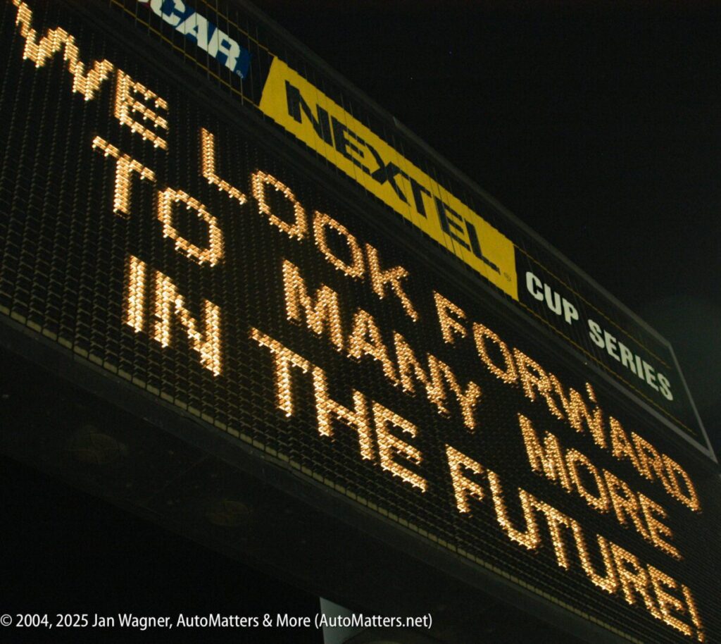 A lit scoreboard displays the message, "WE LOOK FORWARD TO MANY MORE IN THE FUTURE," with sponsorship banners above it at a nighttime event.