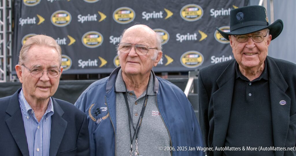 Three older men stand together outdoors in front of a backdrop featuring Sprint and NASCAR logos.