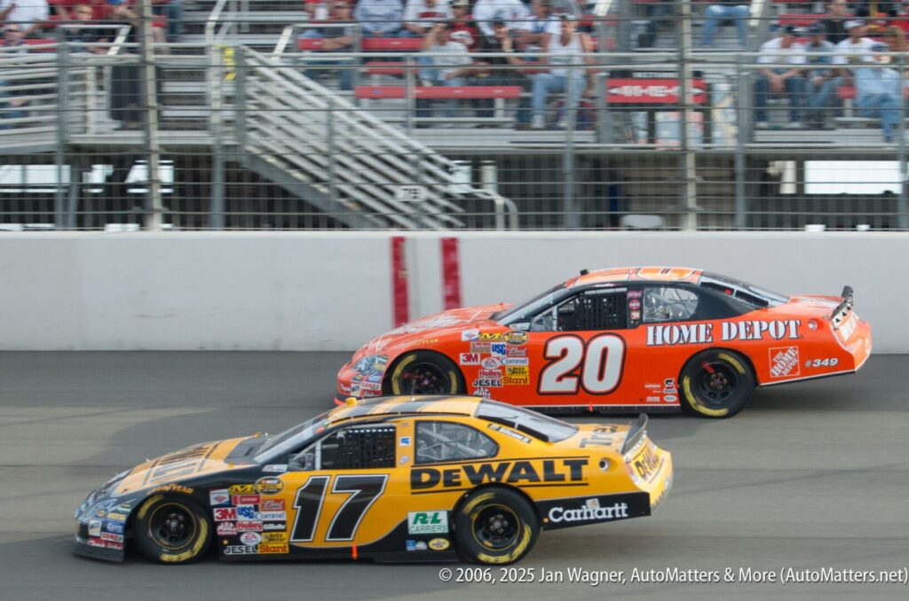 Two NASCAR race cars, number 17 (DeWalt) and number 20 (Home Depot), drive side by side on a track with spectators in the background.