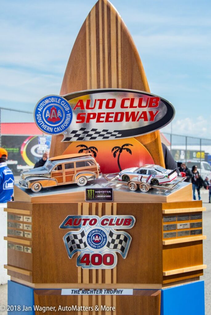 A wooden Auto Club Speedway trophy with a surfboard design and model cars, labeled "Auto Club 400" and "The Richter Trophy.