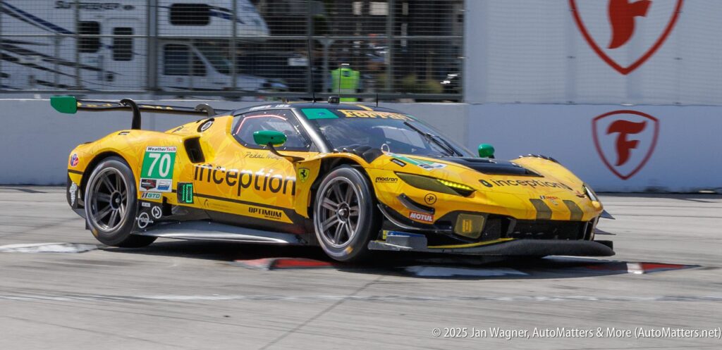 A yellow and black Inception Racing Ferrari race car, number 70, speeds on a racetrack during a motorsport event.