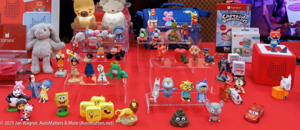 A display of various colorful figurines and toys, including cartoon and animal characters, arranged on clear stands on a red table.