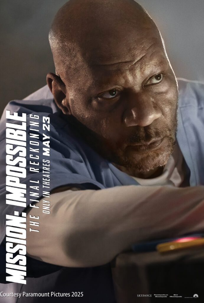 A man in a blue shirt looks upward with a serious expression. Text reads “Mission: Impossible – The Final Reckoning, only in theaters May 23. Courtesy Paramount Pictures 2025.”.