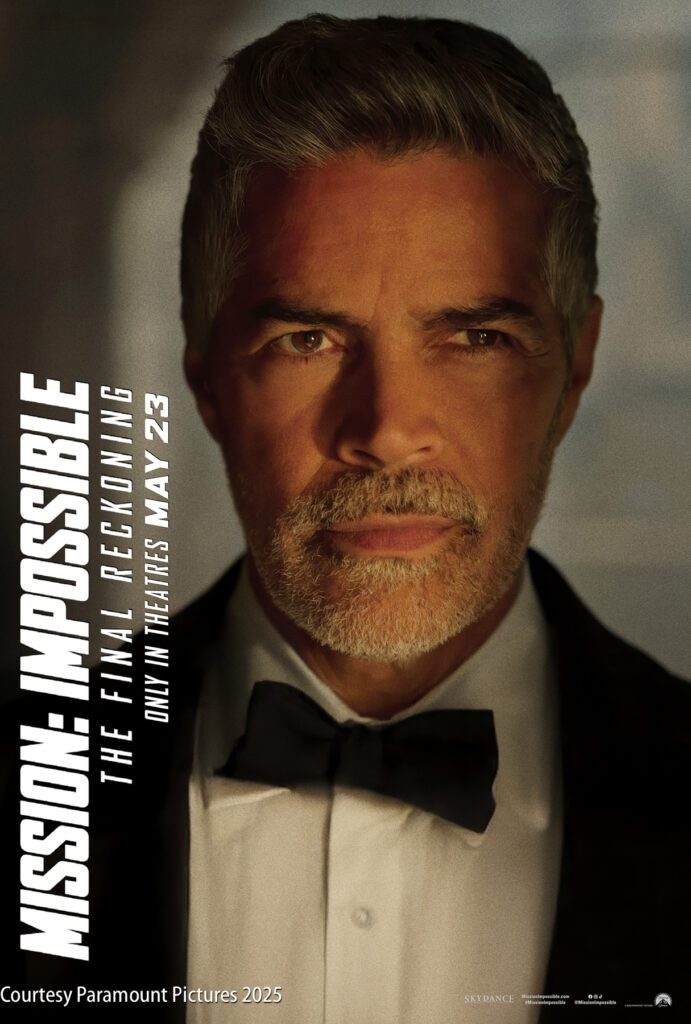 A man in a tuxedo stands in dramatic lighting. The “Mission: Impossible – The Final Reckoning” movie title and release date information are displayed on the left side of the image.