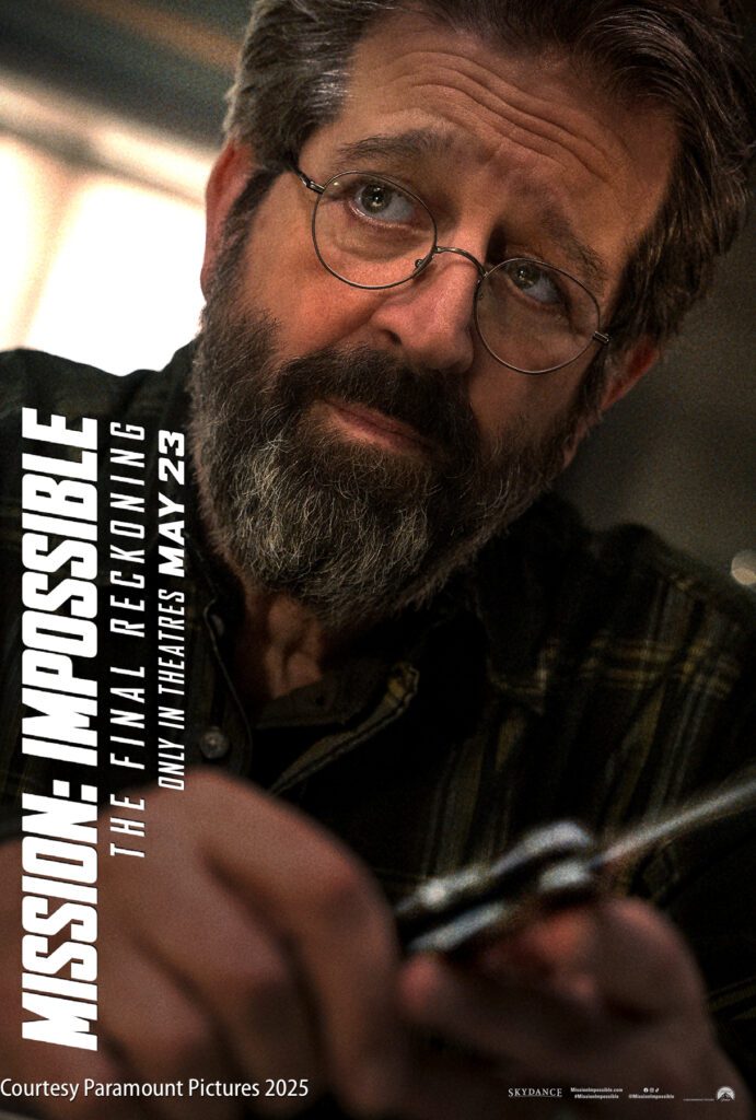 A man with glasses and a beard looks intently while holding an object. Text reads: "Mission: Impossible The Final Reckoning, only in theatres May 23. Courtesy Paramount Pictures 2025.