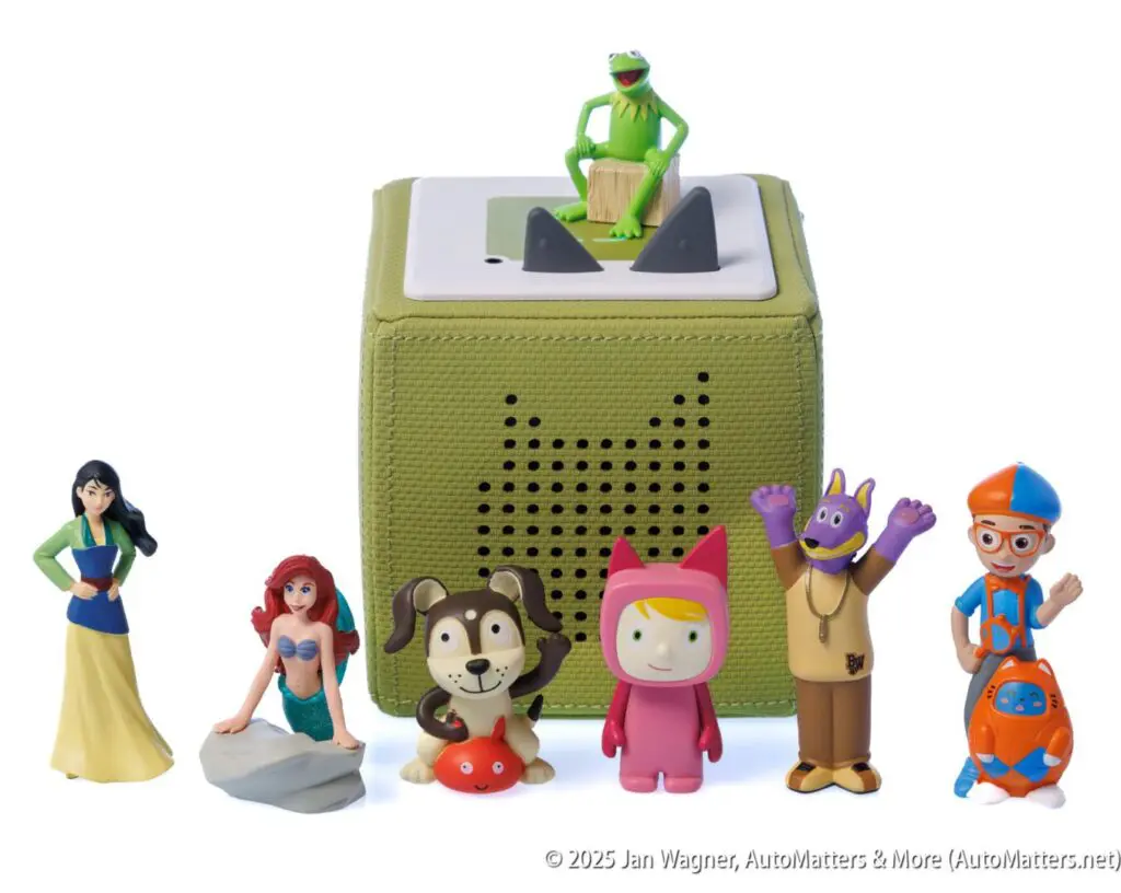 A green audio speaker cube with Kermit the Frog on top, surrounded by six toy figures including Snow White, Ariel, and other cartoon characters.
