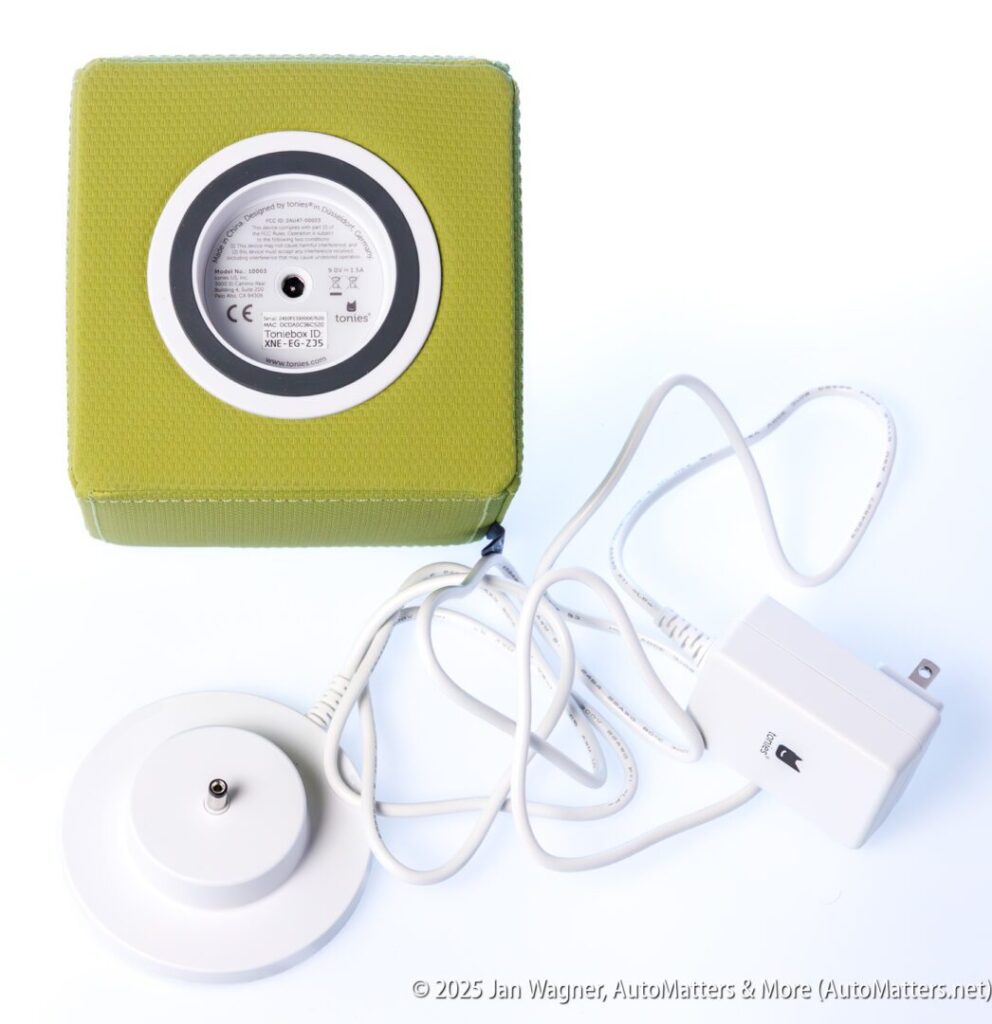 A green cubic electronic device with a circular base, a white power adapter, and a connected charging cable, shown on a white background.