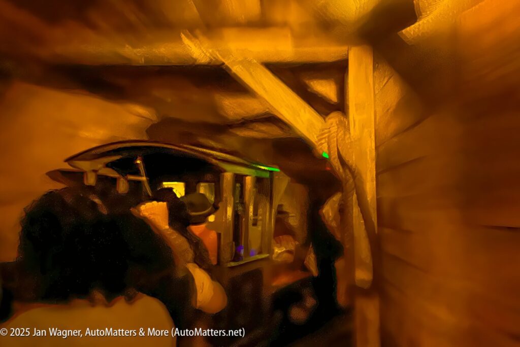 Passengers ride a dark, wooden amusement park attraction while seated in a vehicle, surrounded by wooden beams and dim, warm lighting.