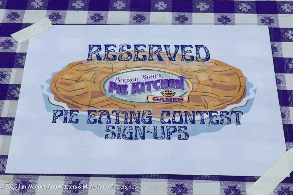 A printed sign on a checkered tablecloth reads "Reserved Boysen Bear's Pie Kitchen Games Pie Eating Contest Sign-Ups.