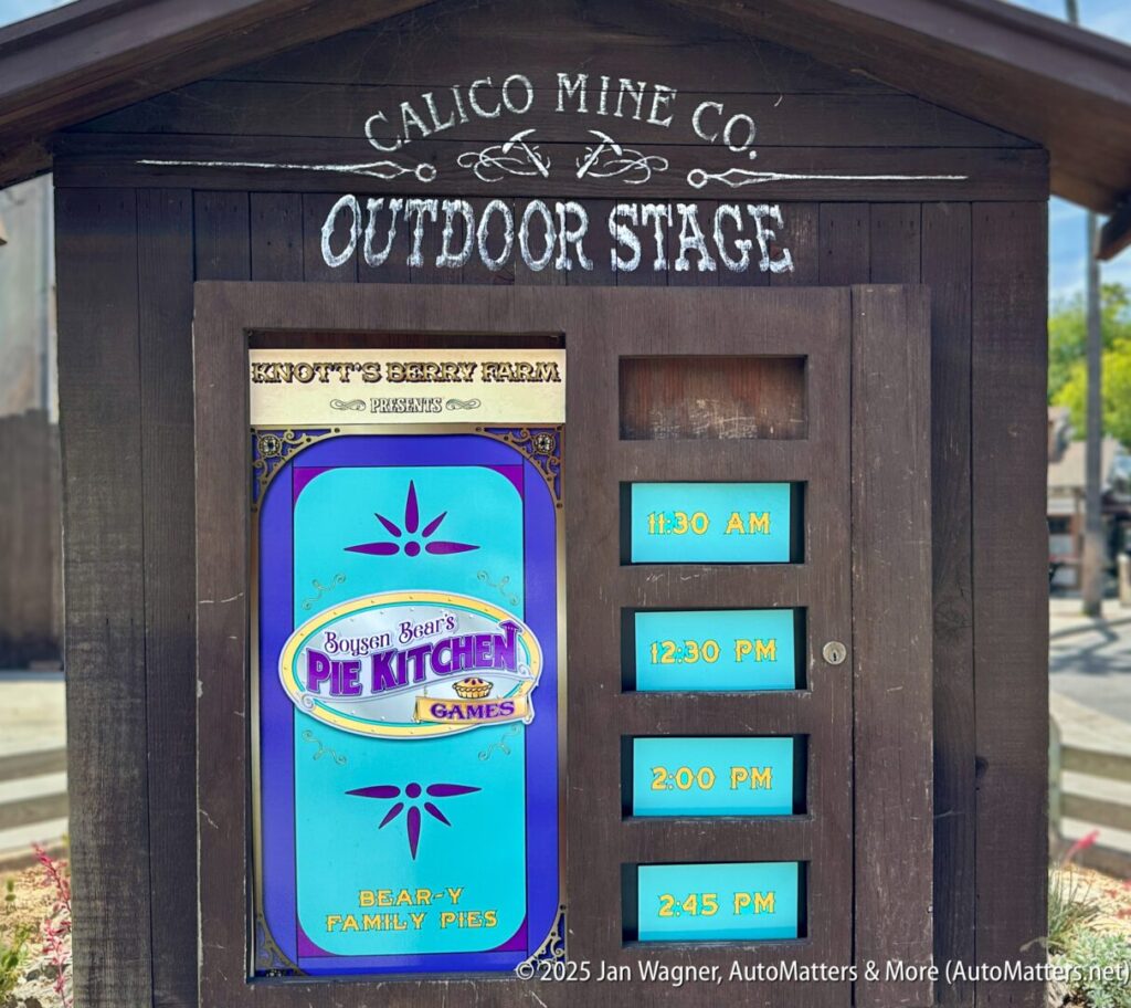 Wooden sign for Calico Mine Co. Outdoor Stage displays showtimes (11:30 AM, 12:30 PM, 2:00 PM, 2:45 PM) and a poster for Boysen Bear’s Pie Kitchen family pies game.